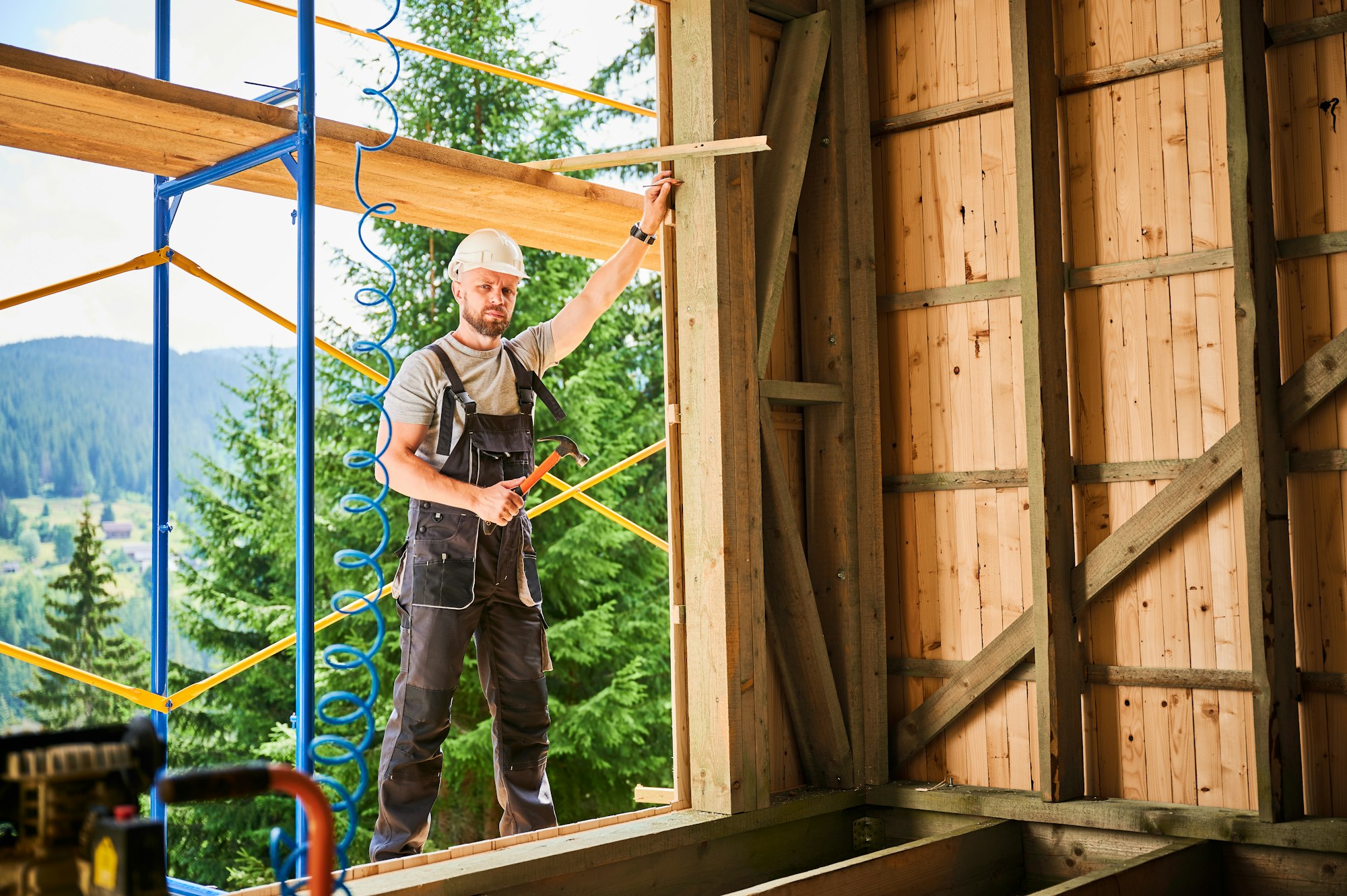 Carpenter constructing wooden frame house.