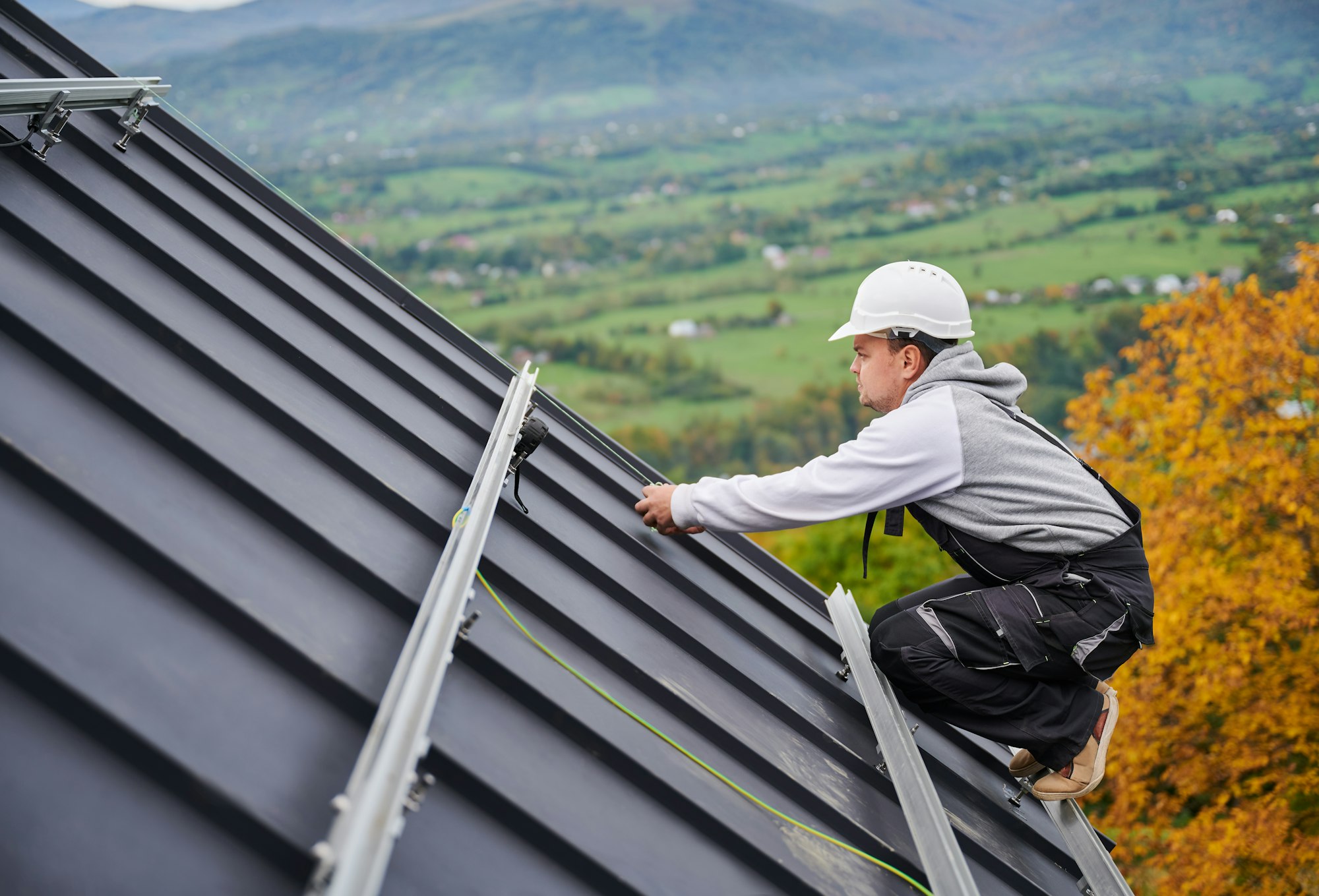 Man worker prepearing for mounting photovoltaic solar modules on roof of house.